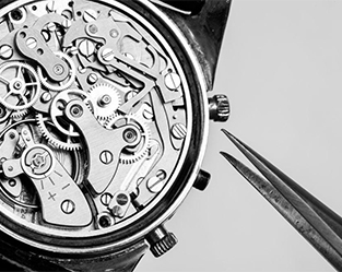 Detailansicht des Uhrwerks einer mechanischen Armbanduhr mit sichtbaren Zahnrädern und Bauteilen, daneben eine Pinzette – Symbolfoto für das Aufziehen mechanischer Uhren