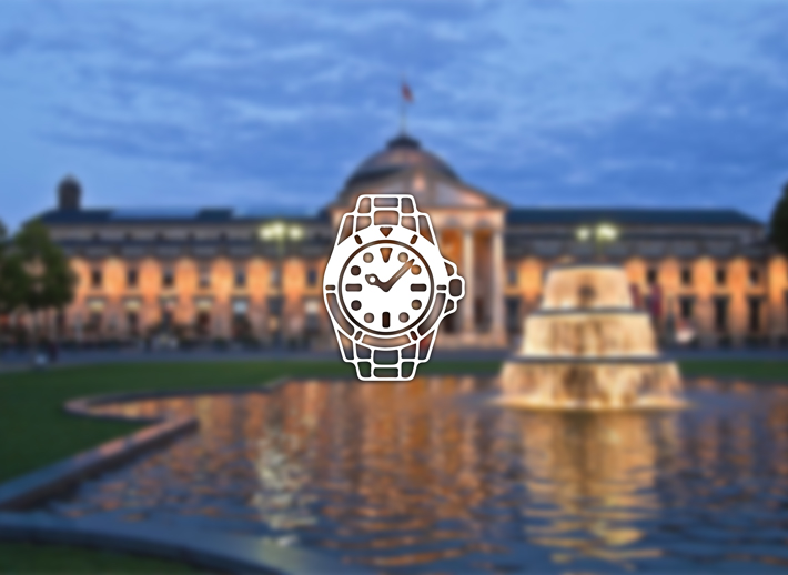 Wiesbaden mit dem Kurhaus und beleuchtetem Springbrunnen am Abend – Symbolfoto für Rolex verkaufen und Ankauf in Wiesbaden